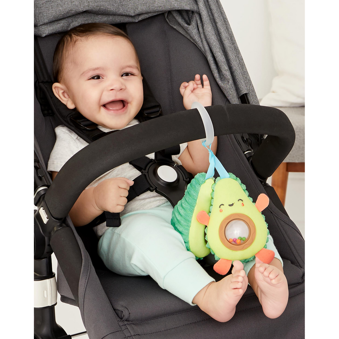 Plush avocado stroller toy with peek-a-boo rattle pit