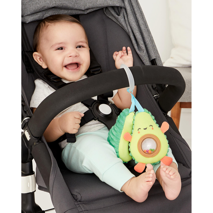 Plush avocado stroller toy with peek-a-boo rattle pit